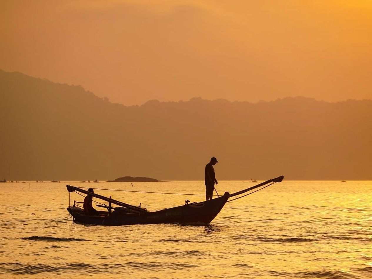 Guia remando canoa em rio com floresta ao fundo