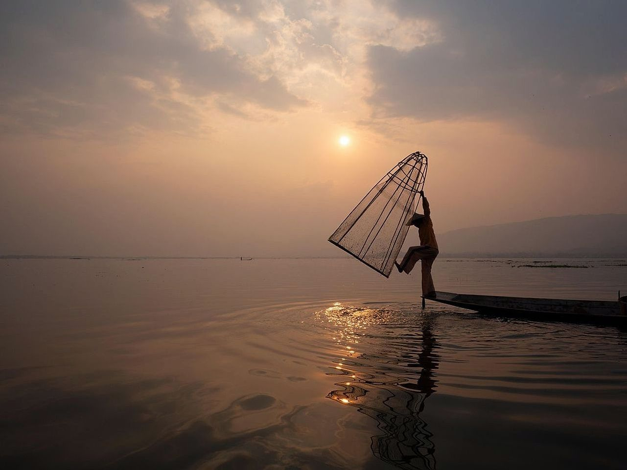 Pescador fisgando peixes em águas cristalinas durante o amanhecer